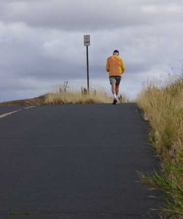 Jogger in orange runs up a hill. Drinking dairy sport drinks can help rehydrate you after a long run. Read more at MooScience.